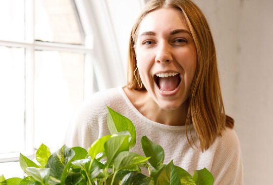 Blonde woman smiling with a plant