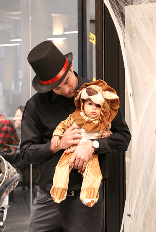 Kaleidoscope Employee Holding Their Kid In Halloween Costumes