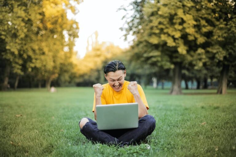 Excited man on a laptop in a park