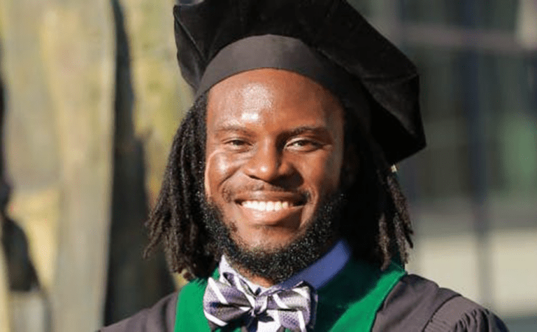 Man smiling with graduation robes on