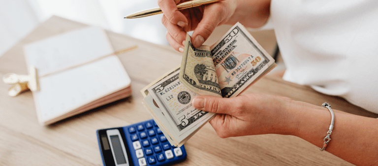 Person counting cash with a calculator and notebook