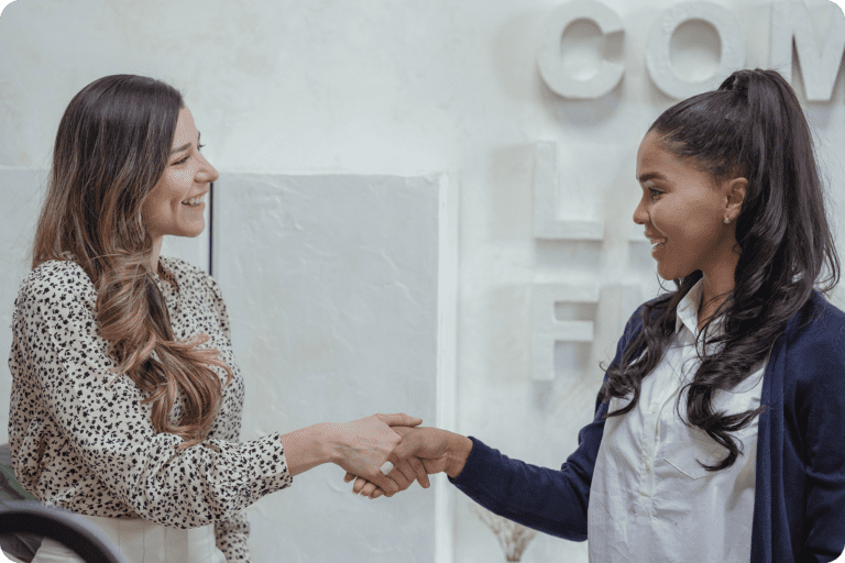 Two women shaking hands in office setting